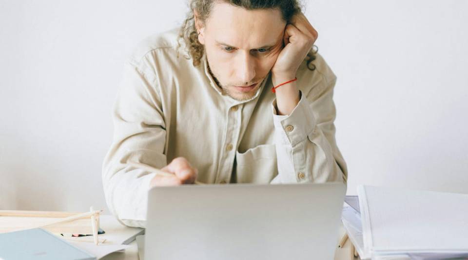 Man staring worried at a laptop